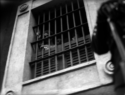 Gente detrás de una ventana con barrotes