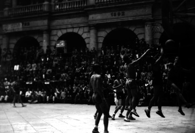 Basquetbolistas juegan debajo de la canasta durante partido en edificio