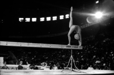 Gimnasta en arco con un pie en la viga de equilibrio