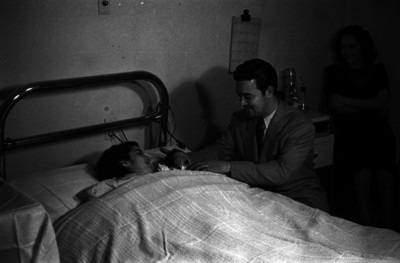 Padre y madre observan a su hijo recién nacido, interior de habitación de un hospital