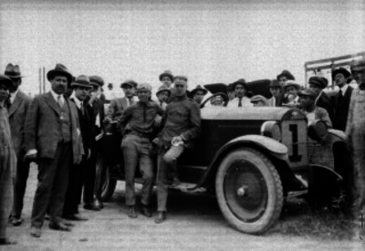 Farell acompañado de varios hombres junto a un auto de carreras, retrato de grupo