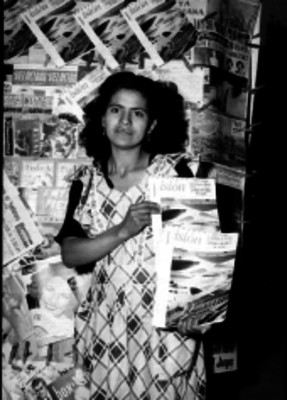 Probable expendedora sosteniendo ejemplares de la revista Visión junto a un puesto de periódicos
