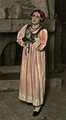 Mimí Aguglia de pie posa con las manos juntas en una escena teatral