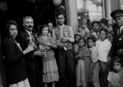 Parejas sosteniendo en brazos juguetes frente a gentes en el interior de una tienda de ropa, retrato