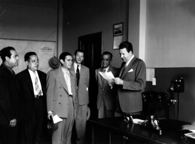 "Raúl de Anda" en una oficina lee un documento ante varios hombres