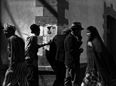 Hombre observa cartel de pelea de box en una calle