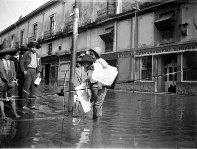 Voceadores conversan en una calle inundada