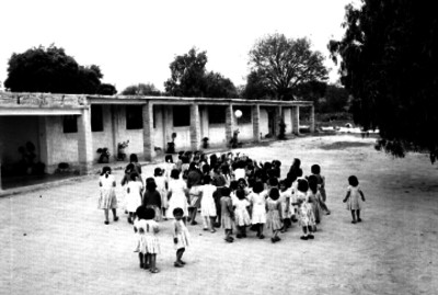 Niñas juegan con una pelota en los patios de la escuela rural
