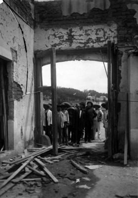 Hombres observan restos de una casa incendiada