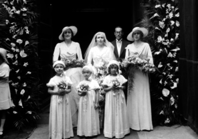 Pareja de novios acompañados de damas de honor en la entrada de una iglesia, retrato de grupo