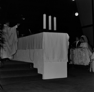 Novios en un reclinatorio frente al altar de una iglesia durante la ceremonia religiosa