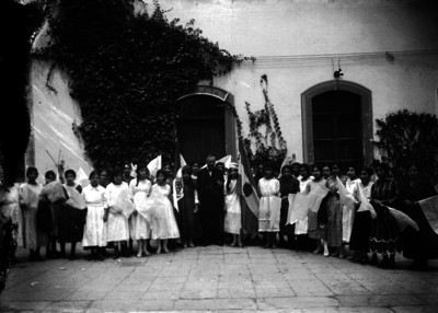 Maestros y alumnas frente a una escuela, retrato de grupo
