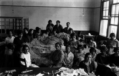 Maestras y alumnas realizando trabajos manuales en un salón