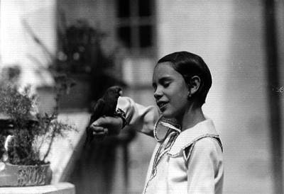 Niña posando con un perico en la mano, retrato