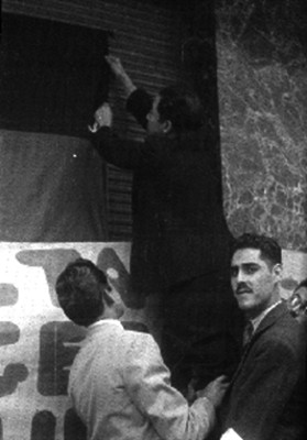 Hombres colocando banderas de huelga fuera de un edificio de la Compañía Telefónica y Telegráfica Mexicana