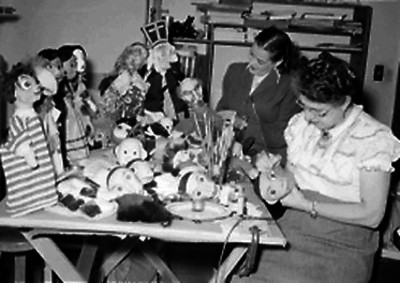 Mujeres realizando máscaras y muñecos de cartón en un taller
