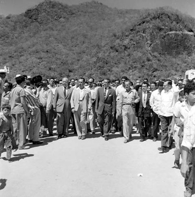 Adolfo López Mateos acompañado de Lázaro Cárdenas y políticos recorriendo alrededores de la presa Zicuirán durante su visita en campaña