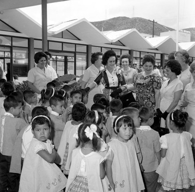 Eva Sámano de López Mateos y comitiva conviviendo con niños en los patios de la guardería Carlota Bernal de Gámez