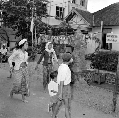Mujeres y niños observando una figura budista en una calle de Balí, Indonesia