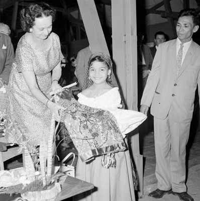 Eva Sámano de López Mateos entregando un vestido a una niña Indonés