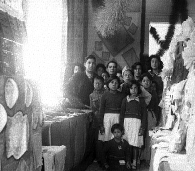 Maestro con alumnos en una exposición de trabajos manuales en un salón, retrato de grupo