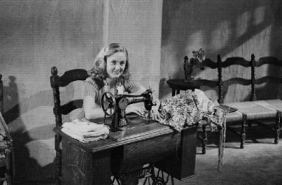 Actriz en una máquina de coser, durante la filmación de una escena cinematográfica