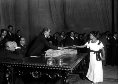 Narciso Bassols entrega reconocimiento a una estudiante durante una ceremonia