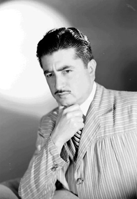 Arturo Corona, actor, porta saco a rayas, con una mano en su barbilla, retrato