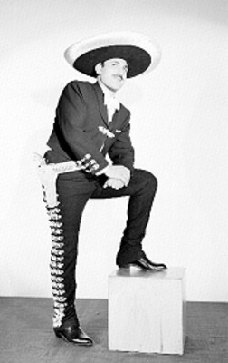 Emilio Dergal, cantante, con traje de charro, con una pierna sobre un cubo de madera, retrato