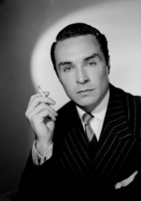 Carlos Agosti, actor, porta traje y lleva cigarro en mano, retrato