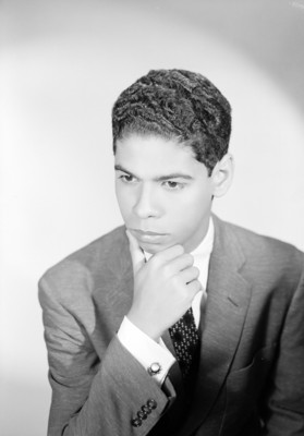 Luis Rafael Sanchez, cantante, mano a la barbilla con actitud reflexiva, viste de traje y corbata, retrato