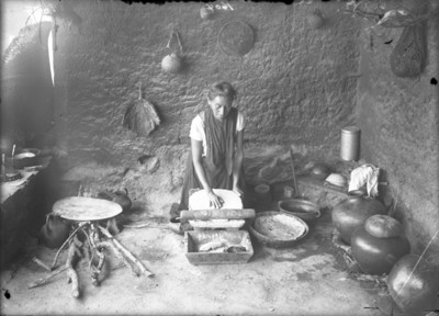 Mujer nahua muele alimentos en un metate