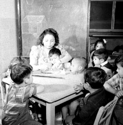 Mujer enseña a niños a dibujar en en salón