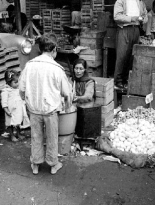 Mujer vende atole a niño en el mercado la Merced