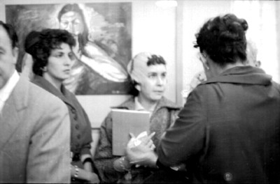 Mujeres conversan junto a una pintura
