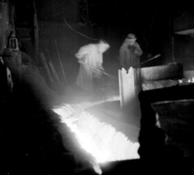 Obrero con traje de protección y herramientas en una fundidora de metal
