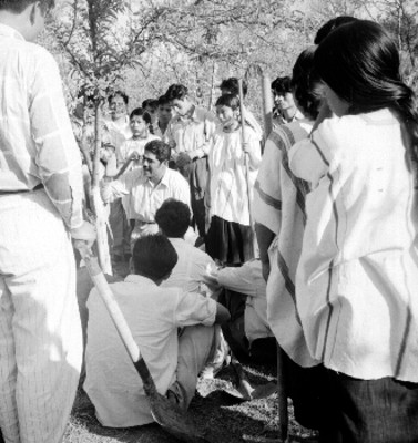 Hombre conversa con indígenas tzotziles en un campo