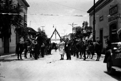 Vicente Estrada y una mujer con una valla de charros en una calle de Xochimilco, retrato de grupo