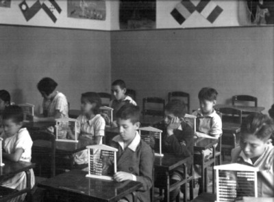 Niños con ábaco en sus pupitres dentro de un aula escolar