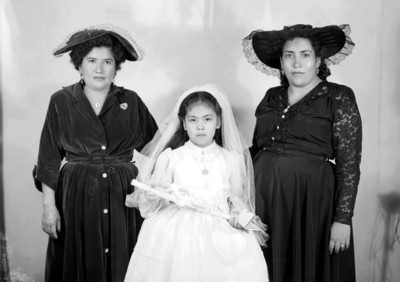 Mujeres con niño vestido para primera comunión, retrato de grupo
