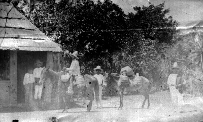 Aguadores con sus burros en patio de una casa rústica