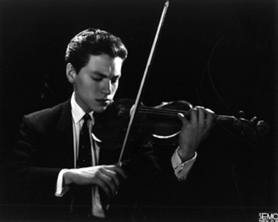 Violinista con instrumento en posición sobre el hombro, fondo oscuro, retrato