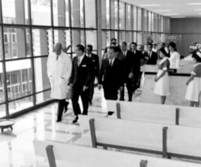Adolfo López Mateos, funcionarios y médicos recorriendo sala de espera de la clínica del IMSS Unidad Revolución durante su inauguración