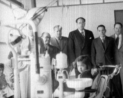Antonio Díaz Lombardo con lideres obreros y periodistas en consultorio de clinica del Seguro Social, retrato de grupo