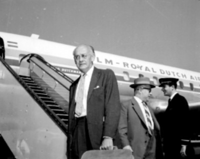 Hombre con equipaje frente a un avión de la KLM, retrato