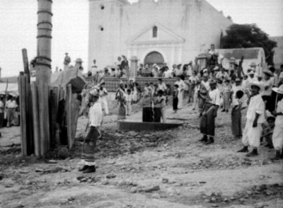 Gente reunida frente a la iglesia de un poblado, para observar el ritual de los voladores de Papantla