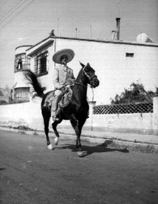 Francisco González de charro cabalgando por la calle de un poblado