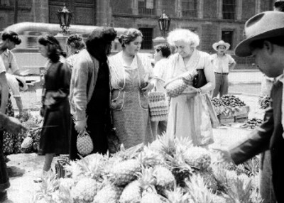 Mujeres comprando piñas en un puesto de la plaza de Santo Domingo