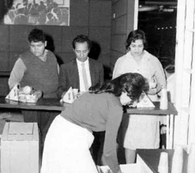 Mujeres colocando abarrotes sobre una mesa en un stand de CONASUPO en la feria del hogar