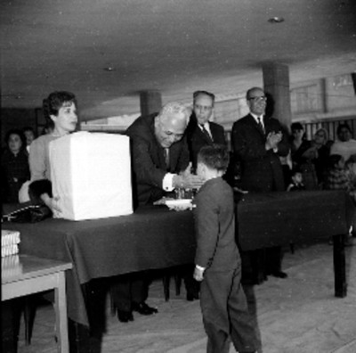 Directivo entregando regalo a estudiante durante la clausura de cursos en una escuela primaria